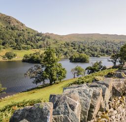 A stone wall with trees and a lake in a valley at Howgill Lodge in Gatebeck near Kirkby Lonsdale