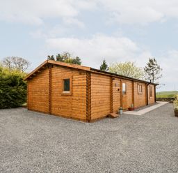 A wooden cabin with gravel surroundings and some plants near Howgill Lodge in Gatebeck near Kirkby Lonsdale