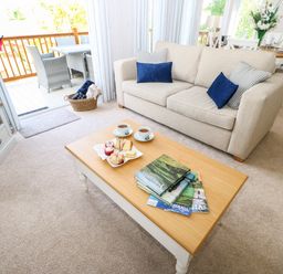 A living room with a beige sofa and blue cushions a wooden coffee table with books and cups visible at Rashierigg in Catterick North Yorkshire