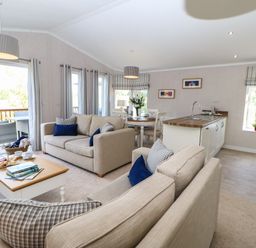 An open plan living area with beige sofas blue cushions a wooden coffee table kitchen island and dining table at Rashierigg in Catterick North Yorkshire