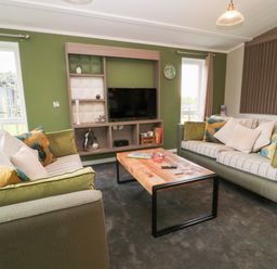 A living room with two sofas a wooden coffee table and a wall-mounted television at Lily in Broadwoodwidger near Ashwater