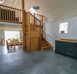 An open kitchen and dining area with wooden stairs and a skylight at Pen y Mynydd in Newport Pembrokeshire