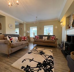 A living room with two sofas and a black and white rug at May Bell Cottage in Dersingham