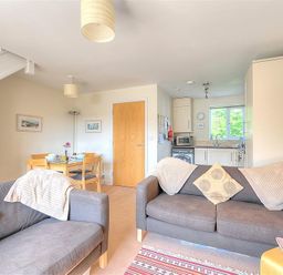A living room with two gray sofas and a dining table with chairs near a kitchen at 1 Coppers Knapp in Lyme Regis