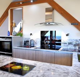 A kitchen with marble countertops an electric stove oven and a sink at Bucket & Spade Lyme Regis