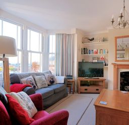 A living room with sofas lamps and a television near a fireplace at 1 Cobb View Lyme Regis