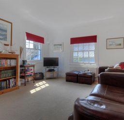 A living room with bookshelves a television and leather sofas at Riverview in Lyme Regis