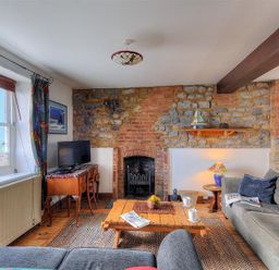A living room with stone and brick walls a wooden coffee table and sofas at Bedrock in Lyme Regis