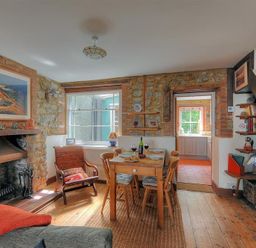A dining area with wooden table and chairs near a fireplace and staircase at Bedrock in Lyme Regis