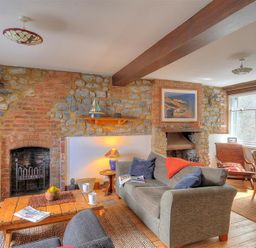 A sitting room with stone walls a wooden coffee table and sofas at Bedrock in Lyme Regis