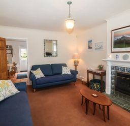 A living room with blue sofas a wooden coffee table and a fireplace at 2 Kersbrook Gardens Lyme Regis