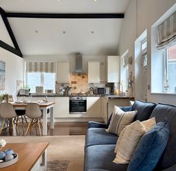 A living room with a kitchen area and dining table at 11 The Gables in Lyme Regis