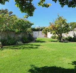 A garden with grass trees and stone walls at The Lower Deck in Lyme Regis