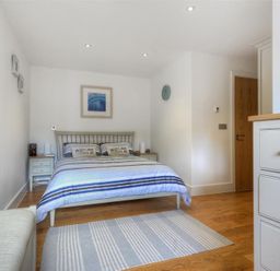 A bedroom with a double bed bedside tables a rug and a mirror on the wall at The Lower Deck in Lyme Regis