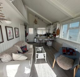 A living room with a sofa, coffee table, kitchen and dining area at 8 Bowling Green Chalets Lyme Regis