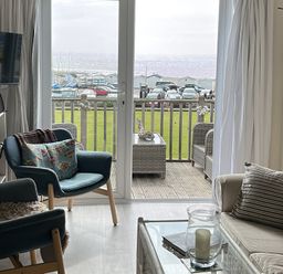 A living room with a view of the coastline at 8 Bowling Green Chalets in Lyme Regis