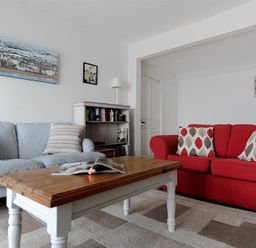 A living room with blue and red sofas a wooden coffee table and wall art at Ross House in Lyme Regis