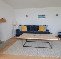 A living room with blue sofas yellow and light blue cushions a wooden coffee table and a wood burning stove at Ancient Lights in Lyme Regis