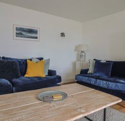 A living room with two blue sofas cushions wooden coffee table and a lamp at Ancient Lights Lyme Regis