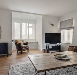 A living room with a leather chair near window a TV on stand and a wooden coffee table at Ancient Lights Lyme Regis