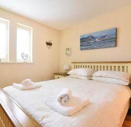 A bedroom with a wooden bed with white bedding and towels on it with two bedside tables and lamps at 2 Buckfields Lyme Regis