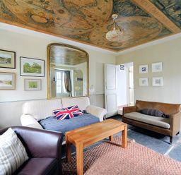 A living room with sofas a wooden coffee table wall art and a ceiling map at 10 Cobb Terrace in Lyme Regis