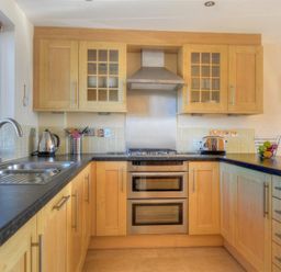 A kitchen with wooden cabinets a stainless steel sink a kettle toaster and a fruit bowl at 8 Driftwood West Bay