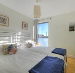 A bedroom with two single beds side by side with white bedding and blue throws at 8 Driftwood in West Bay