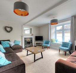 A living room with sofas a coffee table two blue chairs and a window seat at Mermaid House in Lyme Regis