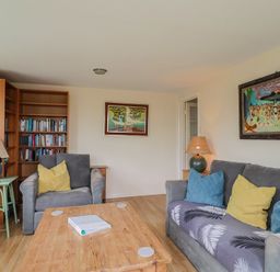A living room with a sofa and bookshelf at Penny Plot Cottage in Lyme Regis
