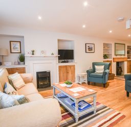 A living room with sofas armchairs a coffee table and a fireplace at Nutwood in Charmouth