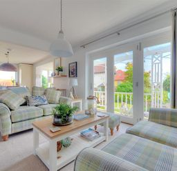 A living room with plaid sofas a wooden coffee table and large glass doors looking out on a garden at Highpoint Lodge in Lyme Regis