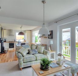 A living room with a sofa and coffee table next to large glass doors leading to a garden at Highpoint Lodge in Lyme Regis