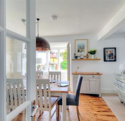 A dining area with a wooden table and chairs next to a living room with a couch and framed pictures at Highpoint Lodge in Lyme Regis
