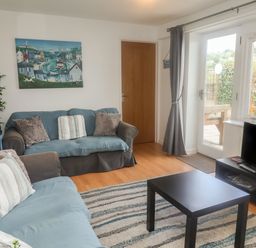 A living room with two sofas a coffee table a television and a large window at Bay View in Lyme Regis
