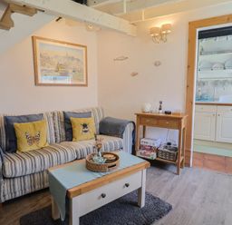 A living room with a sofa and kitchenette at Cleve Cottage in Lyme Regis