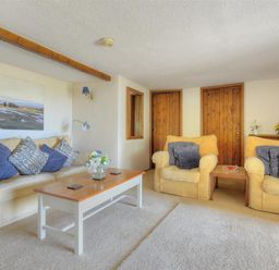 A living room with sofas cushions a coffee table and wooden doors at Willows in Charmouth