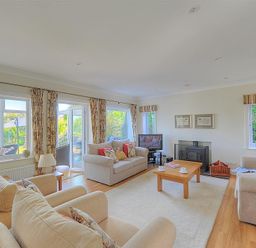 A living room with beige sofas a wooden coffee table and a fireplace at Somerhill in Lyme Regis