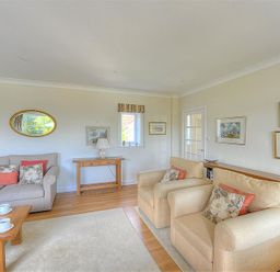 A sitting room with sofas armchairs wooden table and framed pictures on the walls at Somerhill Lyme Regis