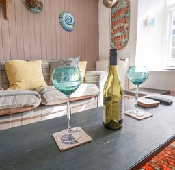 A living room with blue wine glasses on a table and a sofa behind at Coombe Street Cottage in Lyme Regis
