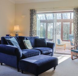 A living room with a blue sofa and glass door at High Cliff Orchard in Lyme Regis