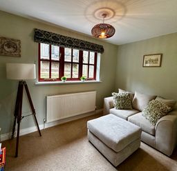 A snug with a sofa and lamp at 28 Barnes Meadow Uplyme