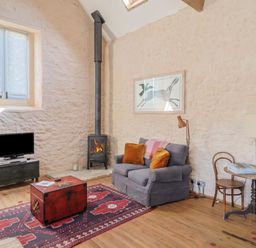 A living room with a sofa and television at The Stone Barn in Bridport