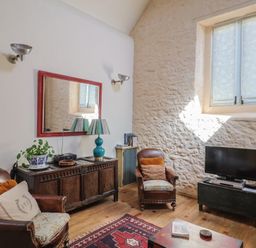 A living room with a sofa, coffee table, and TV at The Stone Barn in Bridport