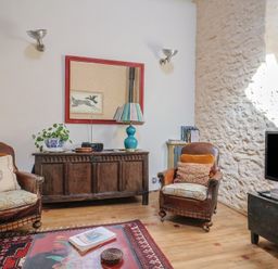 A living room with armchairs and a television at The Stone Barn in Bridport