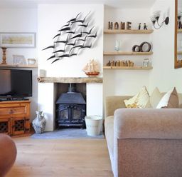 A living room with a wood stove TV wooden shelves and sofa at Bethel Cottage in Lyme Regis