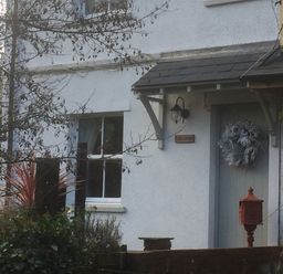 The exterior of a white house with a front door decorated with a wreath and a red mailbox at Bethel Cottage in Lyme Regis