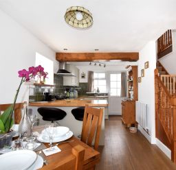 A kitchen and dining area with wooden furniture a staircase and kitchen appliances at Sunnyside in Colyton