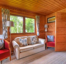 A living room with a sofa and armchairs by windows with curtains and a floor lamp at 4 Pinewood Retreat in Pinewood