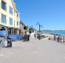 A beachfront promenade with a restaurant and people walking near the sea at Seashore in Lyme Regis